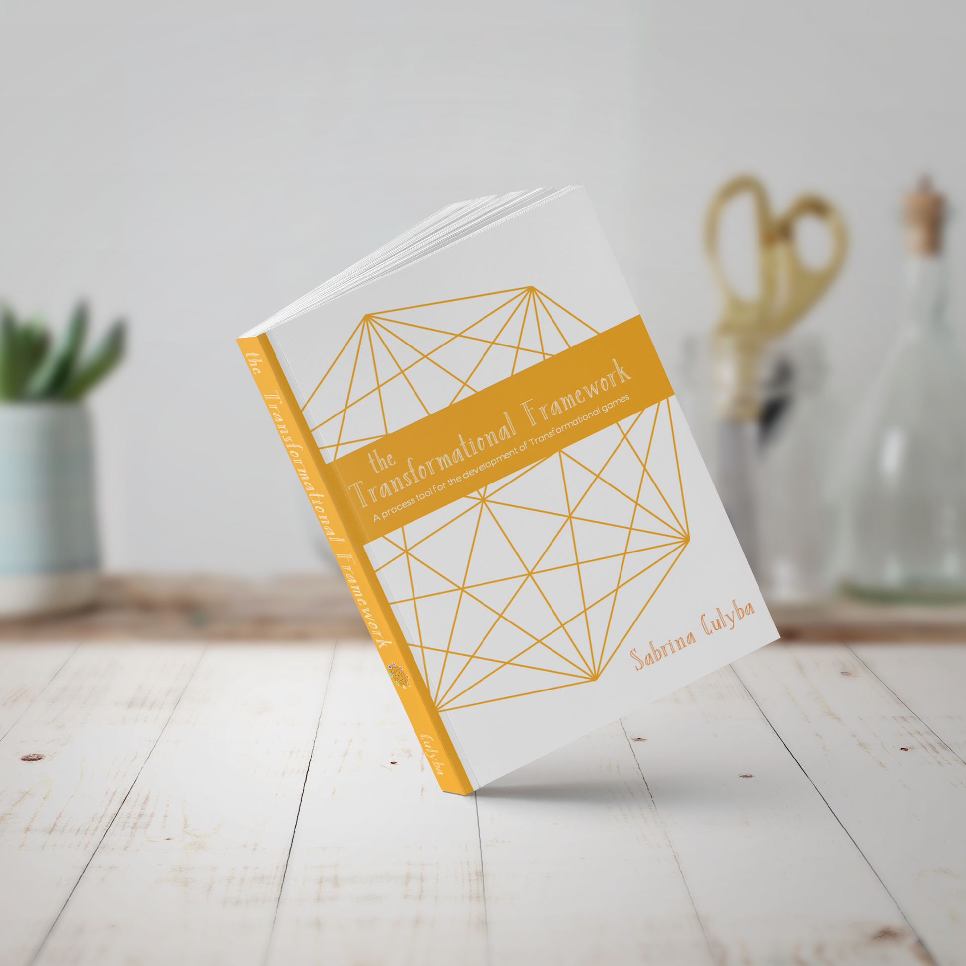 A photo of The Transformational Framework book which has a cover with an orange geometric shape on it.